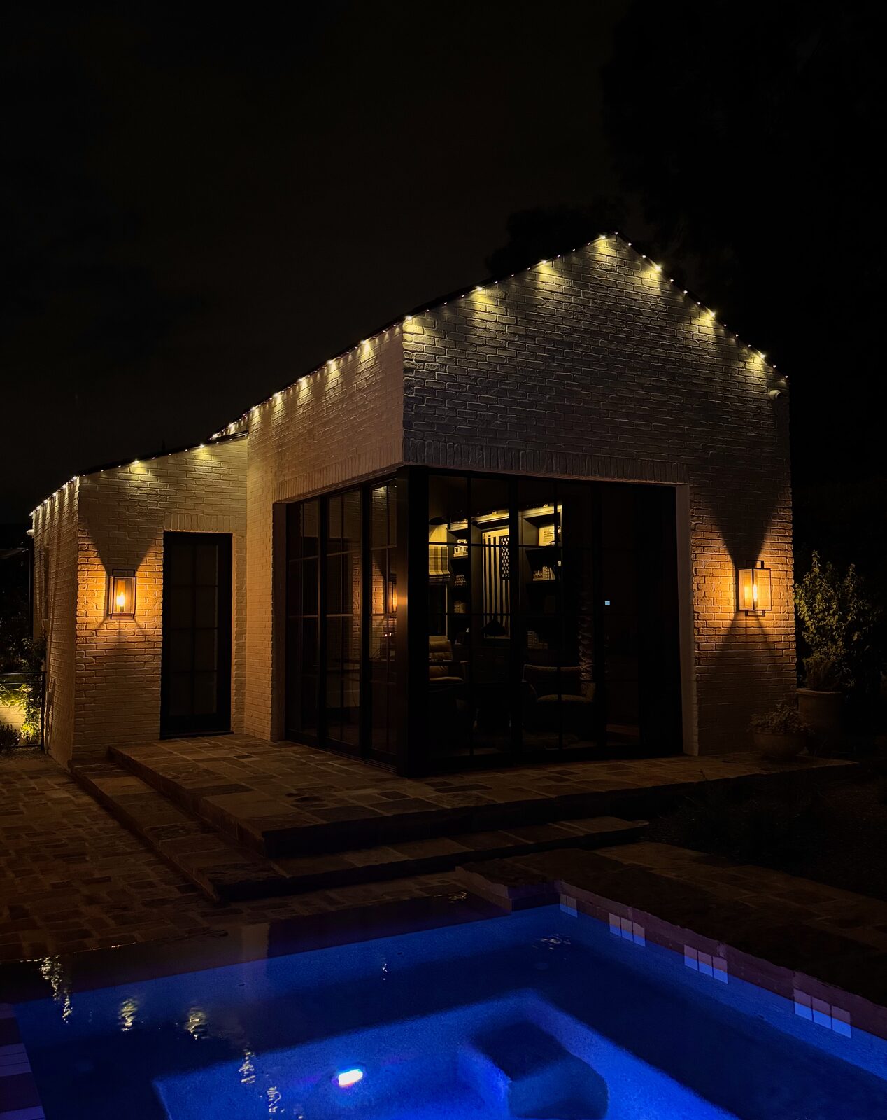 Courtyard entryway with warm white permanent lighting along the eaves