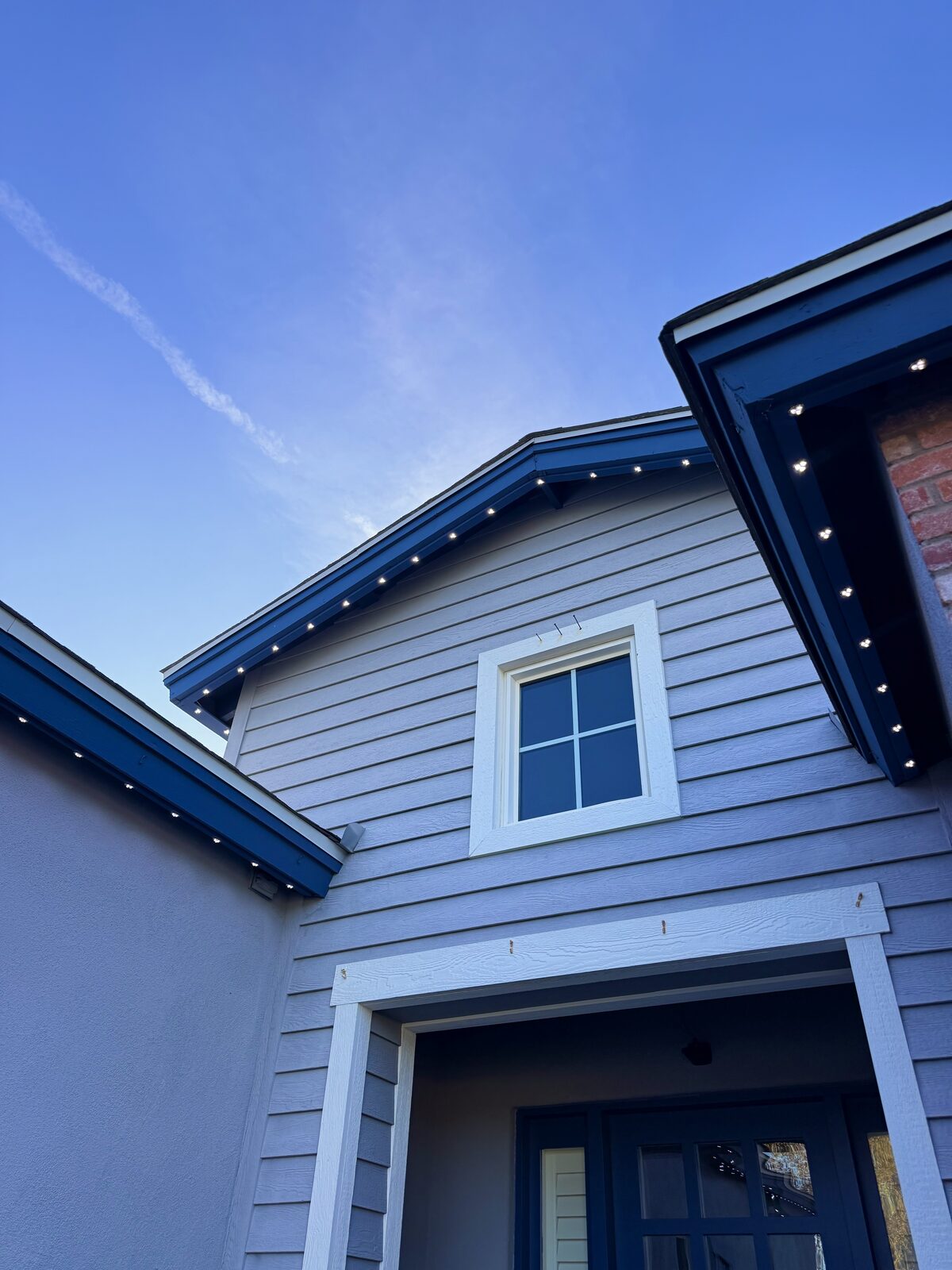 Daytime view of warm white permanent lighting fixtures along a gable roofline