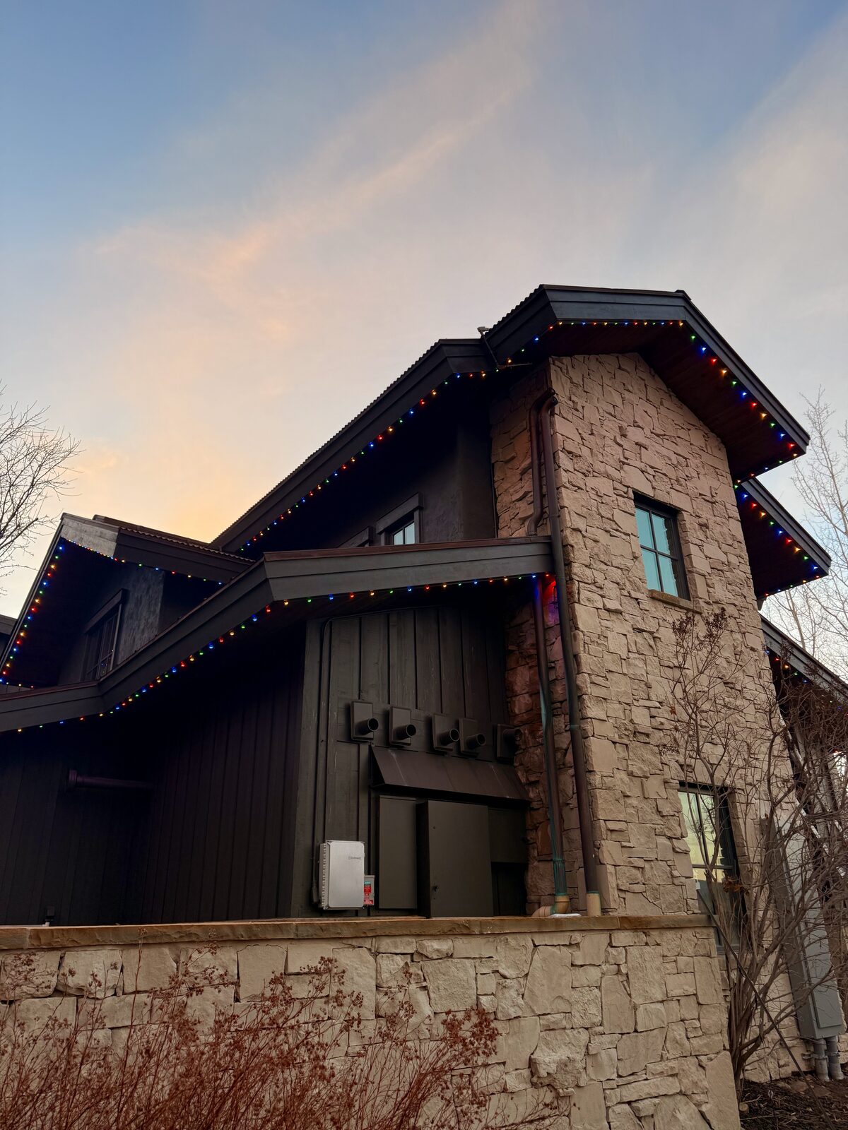 Craftsman-style eaves with warm white permanent lighting at golden hour