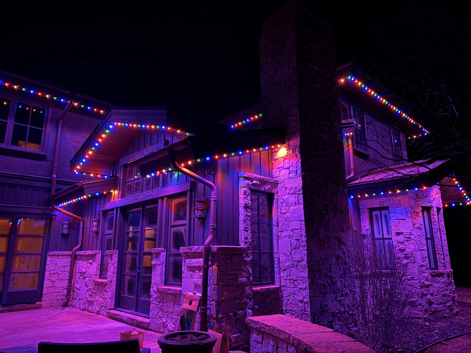 Mountain-style home with warm white permanent lighting along multiple rooflines at night